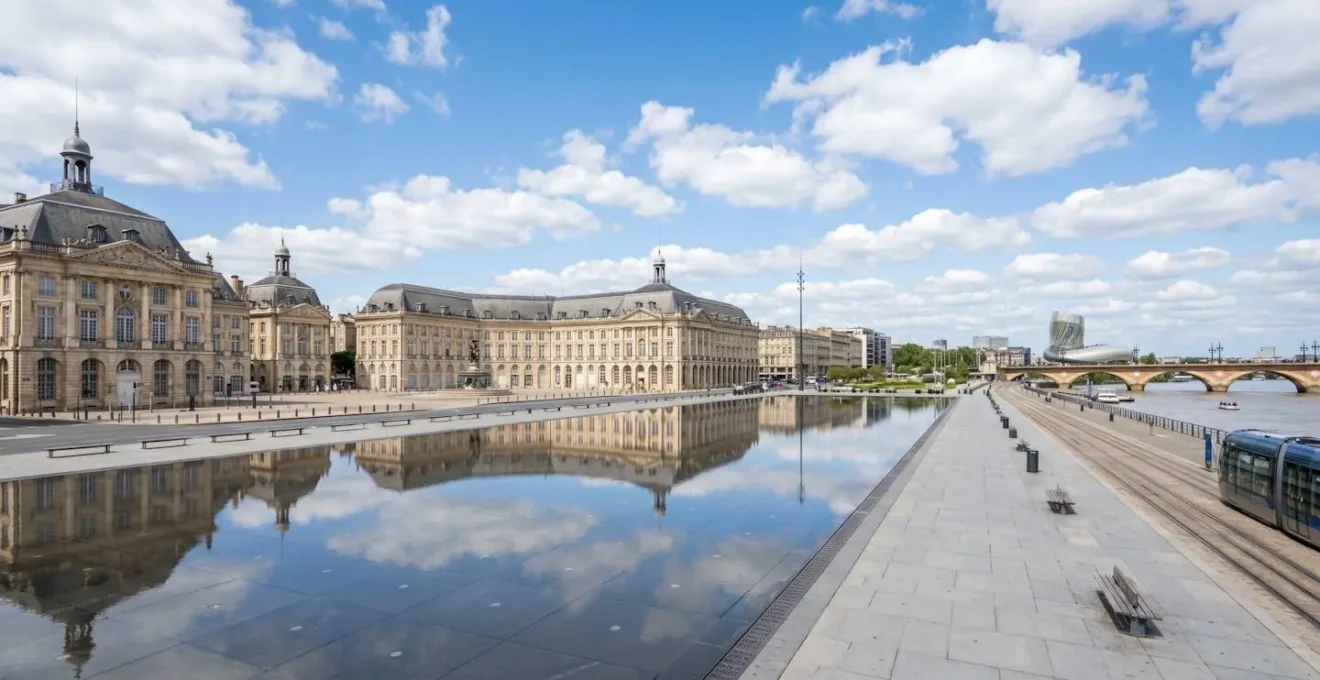 Vue en angle large de la Place de la Bourse à Bordeaux avec ses quais rénovés sous une lumière naturelle de jour